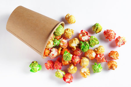 Caramel candy popcorn is scattered from a disposable paper cup on a white backgroundの写真素材