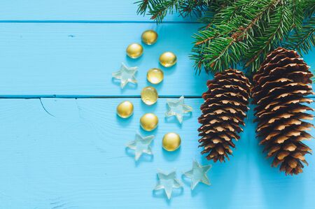 Christmas tree branch with cone on blue wooden background, marbles, starsの写真素材