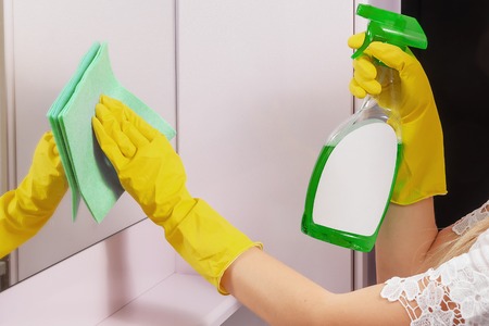 Cleanness in every move. Woman cleans mirror with help of green cloth and special mean of cleaningの写真素材