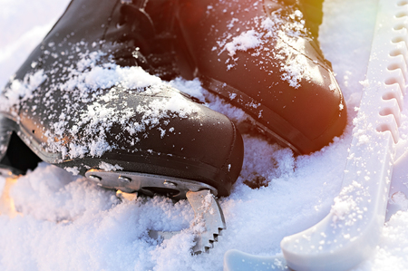 black figure skates lying in the snow and the bright sun. leather, blade, cover, glareの写真素材