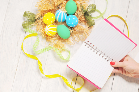 Notebook with eco Easter eggs in nest on rustic white backgroundの写真素材