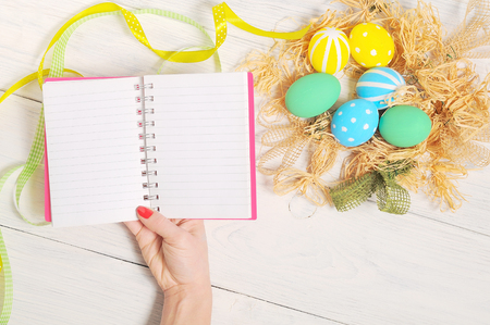 Notebook with eco Easter eggs in nest on rustic white backgroundの写真素材