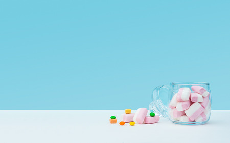 Marshmallow with dragee next to the glass open transparent jar and in itの写真素材