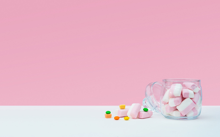 Marshmallow with dragee next to the glass open transparent jar and in itの写真素材