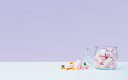 Marshmallow with dragee next to the glass open transparent jar and in itの写真素材