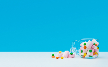 Marshmallow with dragee next to the glass open transparent jar and in itの写真素材