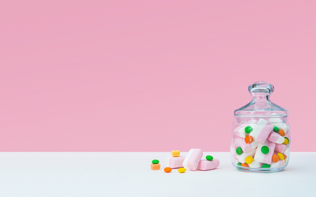 Marshmallow with dragee next to the glass transparent jar and in itの写真素材