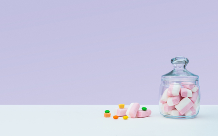 Marshmallow with dragee next to the glass transparent jar and in itの写真素材