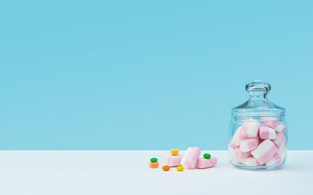 Marshmallow with dragee next to the glass transparent jar and in itの写真素材