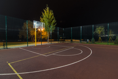 Illuminated basketball playground on red background.の写真素材
