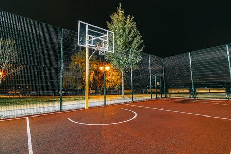 Illuminated basketball playground on red background.の写真素材