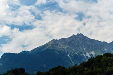Alps peak with forest on front and deep blue skyの写真素材