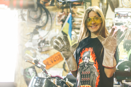 A nice caucasian girl with Angle grinder in workshop with bright lightの写真素材
