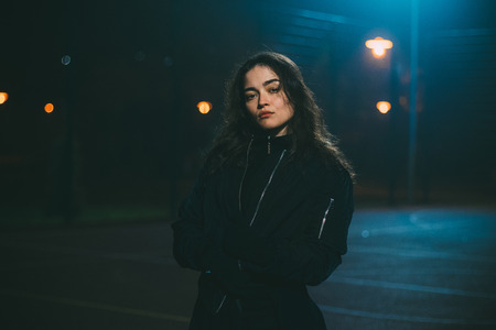 Young caucasian girl on basketball playground in night time and low exposureの写真素材