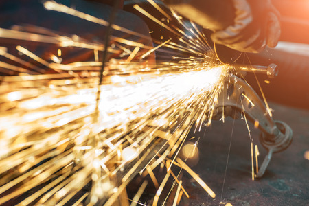 Proffecional worker repair car part with angle grinder. Many sparks on background.の写真素材