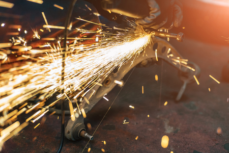Proffecional worker repair car part with angle grinder. Many sparks on background.の写真素材