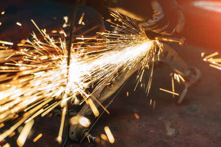 Proffecional worker repair car part with angle grinder. Many sparks on background.の写真素材