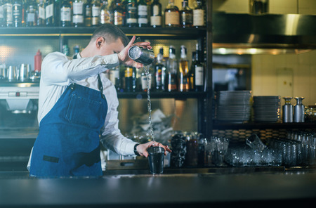 Bartender professionally working with shaker and making good drinksの写真素材