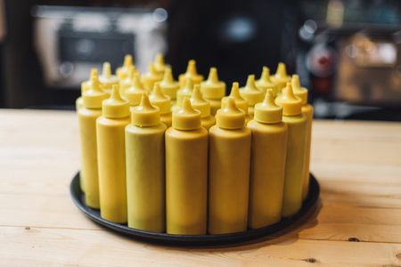 Bottles with mustard on tray in restaraunt interiorの写真素材