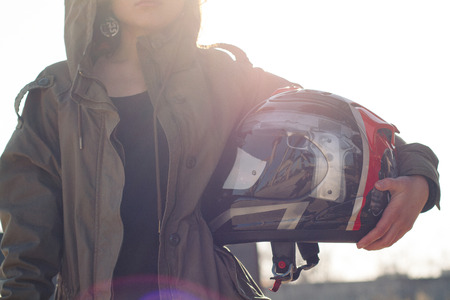 Pretty girl with custom motorcycle helmet in hands with sunbright backgroundの写真素材