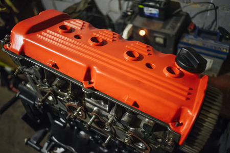 Assembling engine with red valve cap in dark garageの写真素材