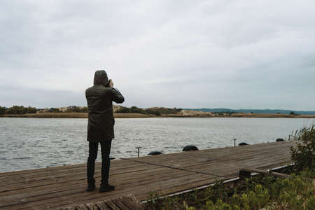 Lonely man staying on pier and shoting nature