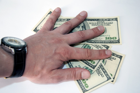 A man's hand with a watch gives a bribe in dollarsの写真素材