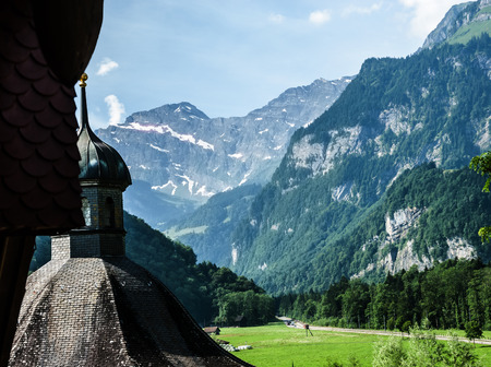 A beautiful summer view of the old church's dome, the green valley and the Alps mountain range in Engelberg, Switzerland. It's a fantastic place for traveller to visit.の写真素材