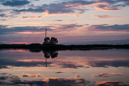 Beautiful summer sunset on the river. Pink and orange clouds reflect in the water, Dnipro river, Ukraine. Concetp - beauty of the nature.の写真素材