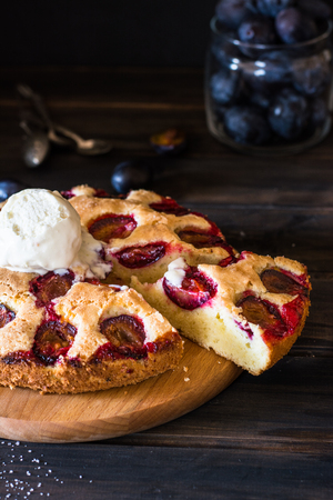 Homemade plum pie on the old wooden background. Still life of food. plum tart. Autumn harvest. Old fashion cuisine. Portion. Plum bakery. Rustic open pie. Winter pie. New York pie. Ice cream.の写真素材