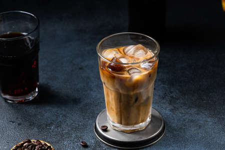 Iced coffee in a tall glass with cream poured over. Iced latte. Cold summer drink. Cold brew in...