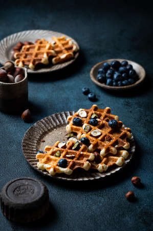 Freshly made belgian waffles with blueberry and hazelnut. Waffles with honey and berry. Place for text. Copy space. Classic sweet breakfastの写真素材