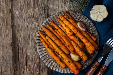 Healthy Homemade Roasted Carrots Ready to Eat. Glazed carrot with herbs and garlic. Fried carrot on wooden background. Sauteed vegetables. Comfort foodの写真素材