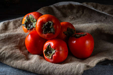 ripe persimmon on wooden background. date-plum or sharon fruit. kaki persimmon fruit. Local food.の写真素材