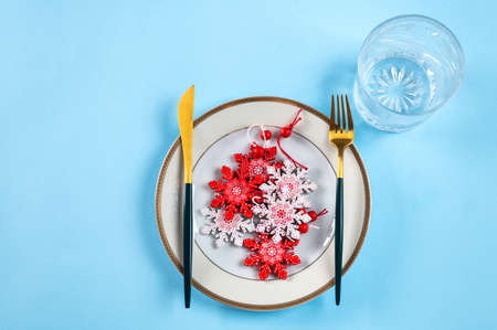 Christmas table setting with modern dishware and decorations on blue background. Top view. New Year...
