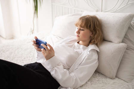 A happy European woman has a video call on her smartphone . The girl looks into the phone camera and...
