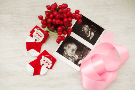 Ultrasound images lie next to children's Christmas socks and a pink ribbonの写真素材