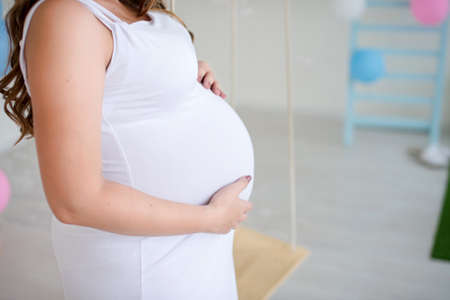 The belly of a pregnant girl who holds it with her hands