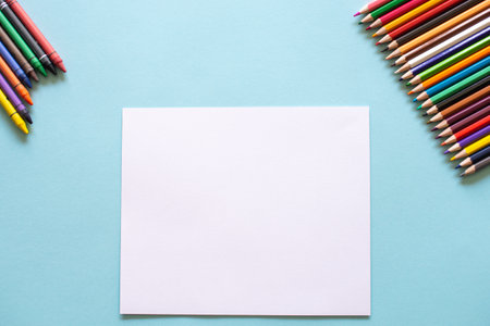 A set of bright stationery on a blue background. colored pencils and white paperの写真素材