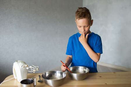 The boy cuts out details from paper. Glue the parts together with glue.の写真素材