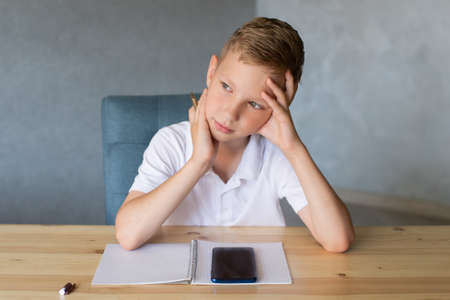 The boy cuts out details from paper. Glue the parts together with glue.