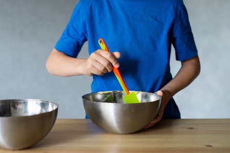 The boy cuts out details from paper. Glue the parts together with glue.の写真素材