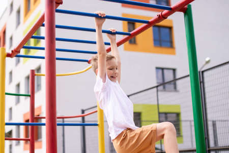 The boy plays sports on the horizontal bars . Arm strength
