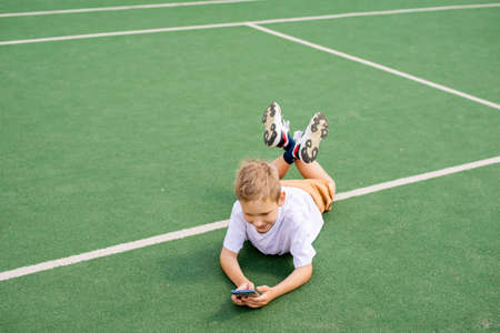 The child looks at the phone and laughsの写真素材