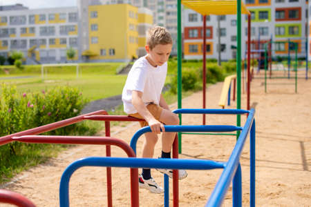 The boy plays sports on the horizontal bars . Arm strengthの写真素材
