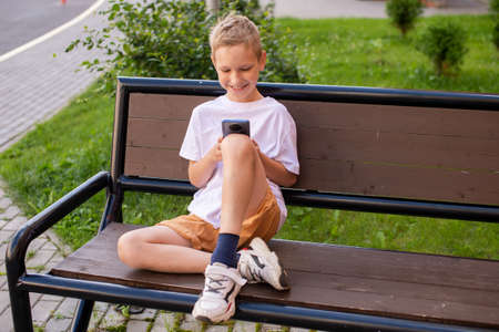 The child looks at the phone and laughsの写真素材
