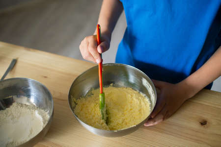 A child prepares dough in metal bowls. Trying the doughの写真素材