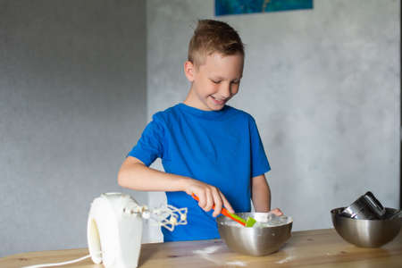 A child prepares dough in metal bowls. Trying the doughの写真素材