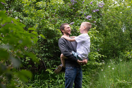 holding a child in your arms, sitting in your arms, studying, dad, son, child, father, parenting, interest development, watching, playing, family vacation, nature walk, spring, flowering treeの写真素材