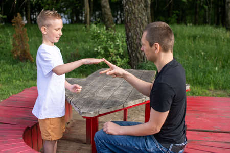 show hands, play with dad, family weekend, white t-shirt, blonde hair, sit on a bench, play in the parkの写真素材